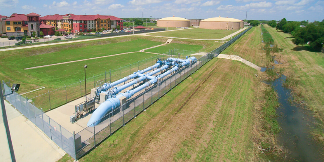 Water treatment pipes near a retention pond on a hill by a water treatment plant in North Fort Bend