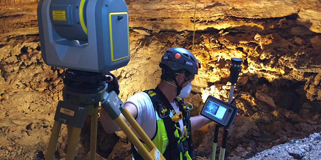 A surveyor looking at readouts on his equipment in the Cambria Cave in Texas