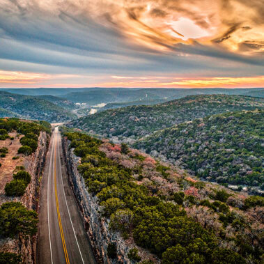 A scenic view of rolling hills in Texas at sunset