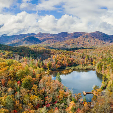 Autumn colored, tree covered hills and a small pond with a pier in North Carolina