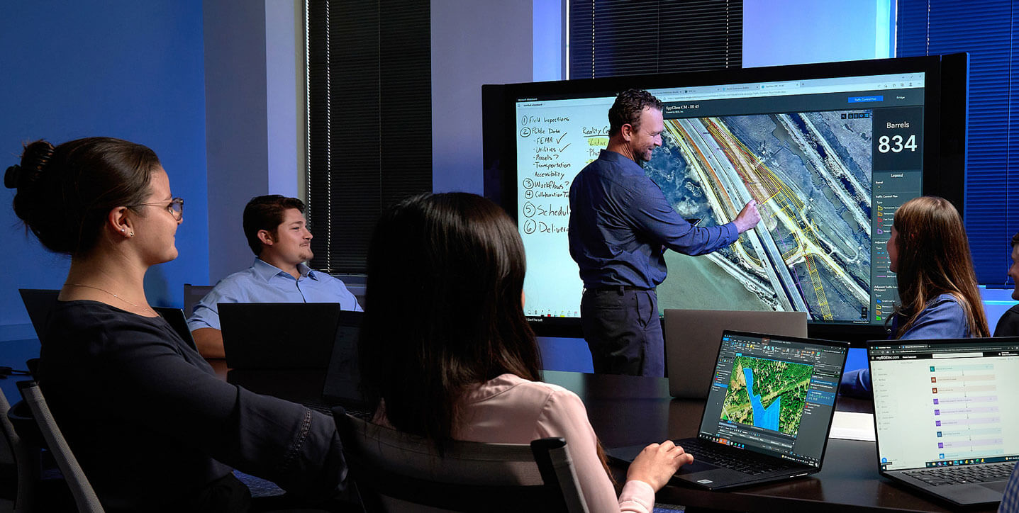 A BGE team leader going over infrastructure plans on an interactive screen during a meeting