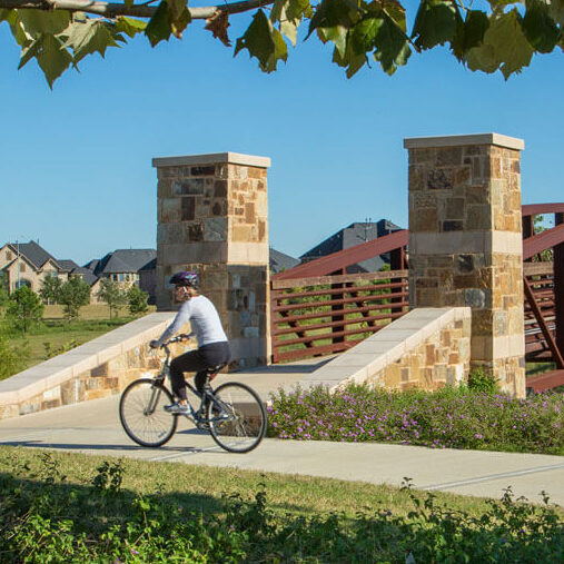 A woman riding her bike by the entrance of a bridge